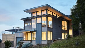 A modern two-story house with large windows and a balcony.