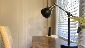 A wooden desk with a black desk lamp, a leather chair, and a book titled "Best American Essays 2017" on the desk. - Charming/Cozy/1 Bedroom (Kansas City)