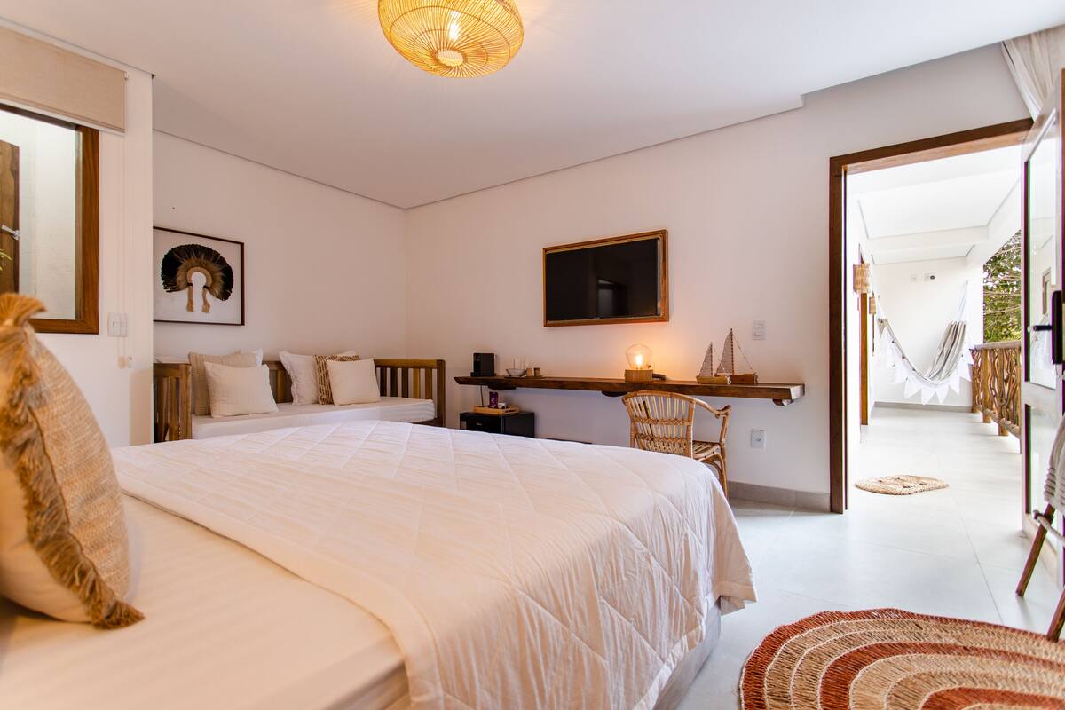 Un dormitorio con una cama grande, una mesita de noche, una silla, una lámpara colgante y vistas al exterior.