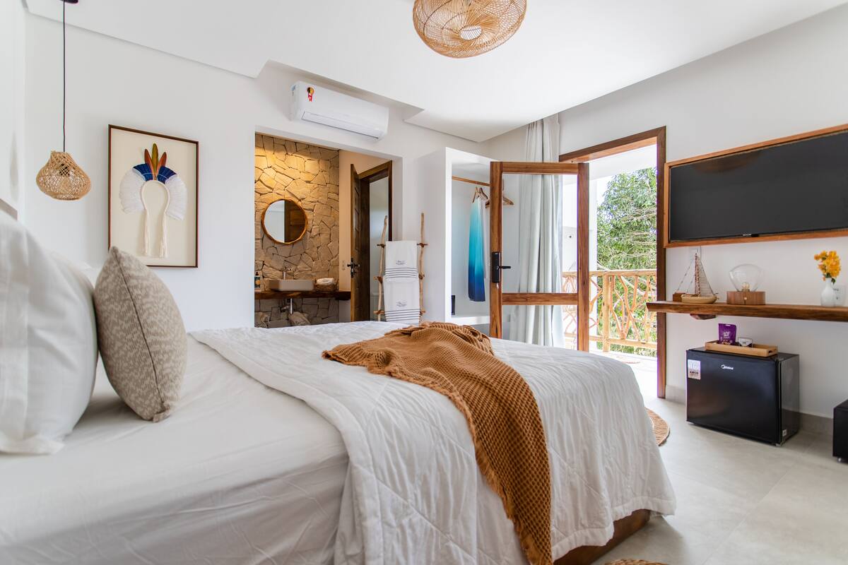 Un dormitorio con una cama grande, una pared de piedra, un espejo y un televisor.