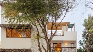 Une villa à deux étages, dotée d’une façade en pierre, d’un toit de chaume et d’une enseigne indiquant « Villa Odara Jericoacoara ».