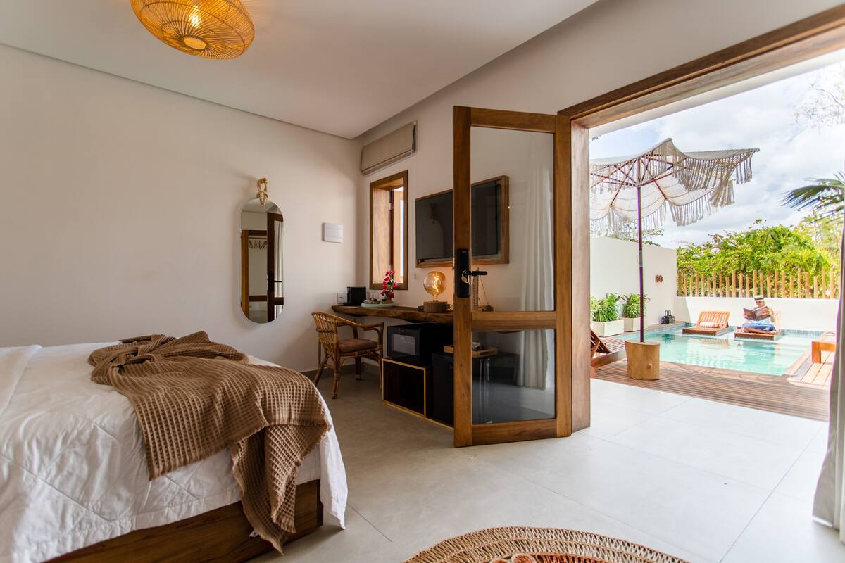 Un dormitorio con cama, escritorio, silla y vista a una piscina al aire libre.