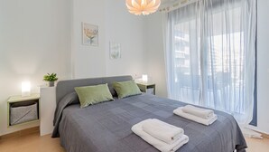 A bedroom with a bed, pillows, a bedside table, a lamp, and a window with sheer curtains. - CALA ALTA beach apartment (Benidorm)