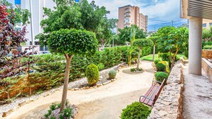 A landscaped garden with pathways, benches, and a variety of trees and shrubs. - CALA ALTA beach apartment (Benidorm)