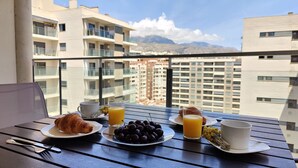 A balcony with breakfast items including croissants, cherries, orange juice, and coffee. - CALA ALTA sunrise apartments (Benidorm)