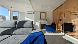 A modern living room with a grey sofa, a blue armchair, and a fireplace. - DON MIGUEL blue sky apartment (Benidorm)