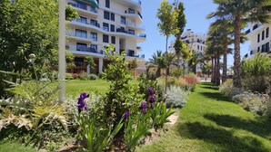 A modern hotel with multiple balconies, lush gardens, and palm trees. - ALLONBAY sun & beach penthouse (Villajoyosa)