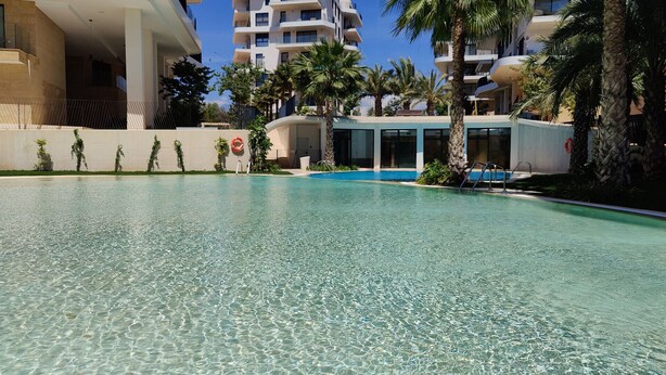 A clear swimming pool with a view of a multi-story building in the background. - ALLONBAY sun & beach penthouse (Villajoyosa)