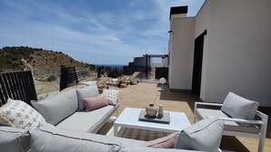 A patio with a white sofa, a small table, and a view of the sea. - ALLONBAY sun & beach penthouse (Villajoyosa)