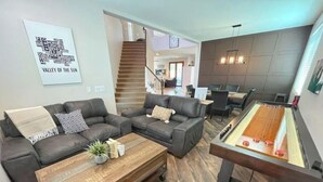 A living room with two sofas, a coffee table, and a pool table.