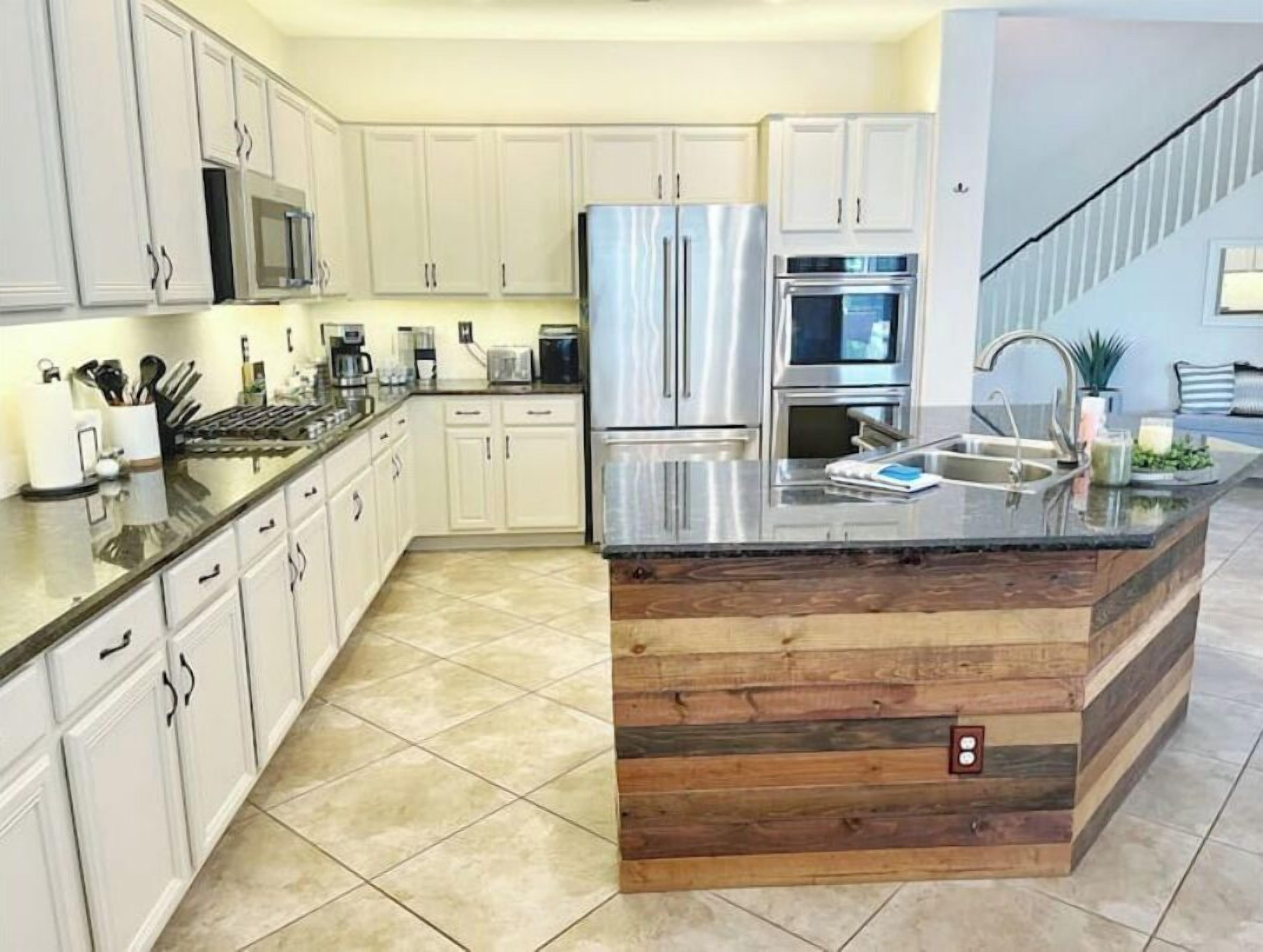 A modern kitchen with white cabinets, stainless steel appliances, and a wooden island.