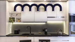 A modern kitchen with a black countertop, stainless steel appliances, and a green dining table. - Our apartment is in a building of the past century, it's on the 2nd floor and served by an elevator.You will have at your disposal 2 bedrooms, 2 bathrooms, and a living room, with a cooking area, that will be able to accommodate up to 5 people.The livi (Roma)
