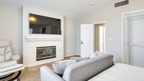 A modern living room with a fireplace, a sofa, a chair, and a door leading to another room. - Spacious Las Vegas Home Near Casinos & Nightlife! (Las Vegas)
