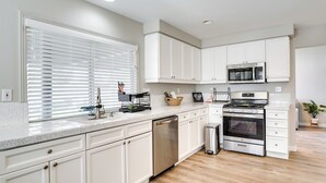 A modern kitchen with white cabinetry, stainless steel appliances, and a wooden floor. - Spacious Las Vegas Home Near Casinos & Nightlife! (Las Vegas)