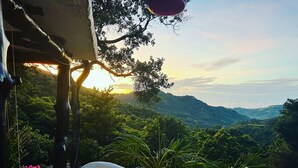 Vista desde un balcón sobre un valle exuberante con montañas al fondo.