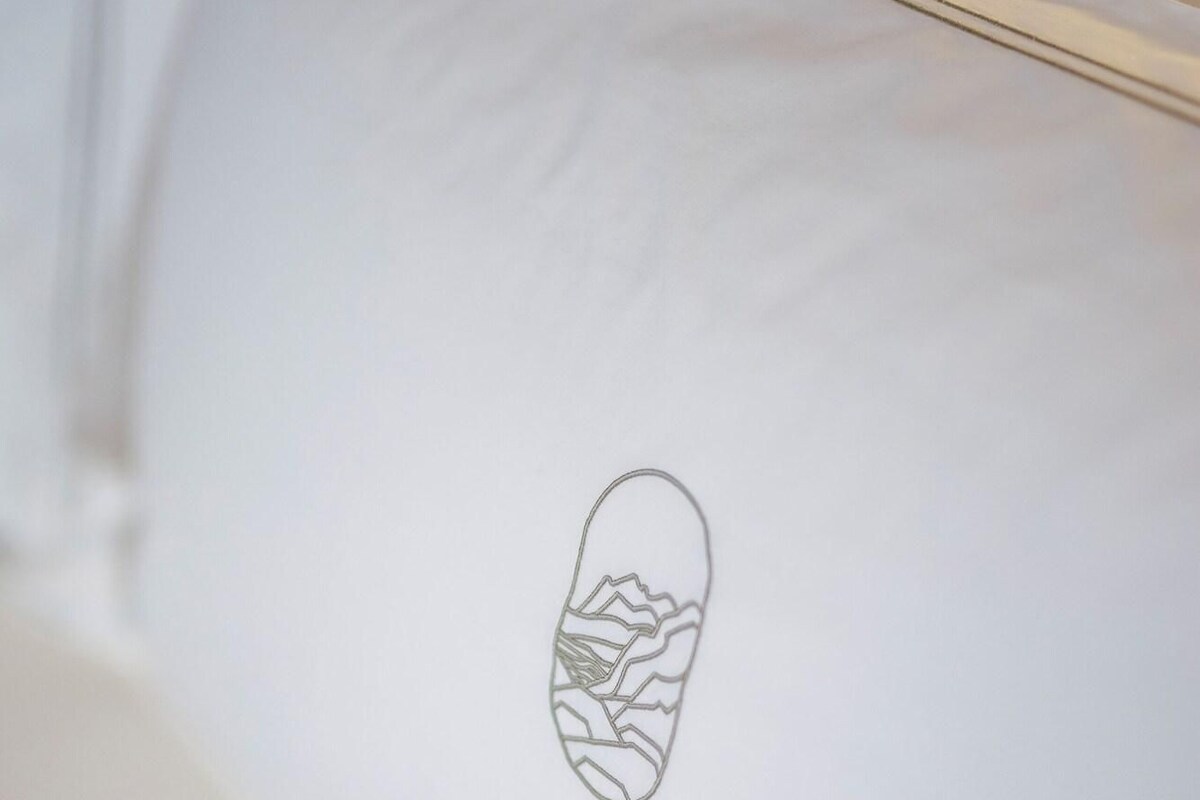 Een wit kussen met een eenvoudige tekening van een berglandschap.