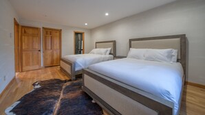 A bedroom with two beds, wooden wardrobe, and a large rug. - NEW OUTDOOR HOT TUB! Luxury 2 Bedroom Suite -The Haüs Windham (Windham)