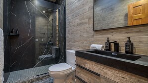 A modern bathroom with a marble vanity, a toilet, and a shower area. - NEW OUTDOOR HOT TUB! Luxury 2 Bedroom Suite -The Haüs Windham (Windham)