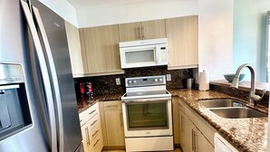Una cocina moderna con electrodomésticos de acero inoxidable, armarios de madera clara y encimera de granito.