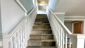 Una imponente escalera con barandillas blancas de balaustre y escalones de mármol que conducen a un rellano.