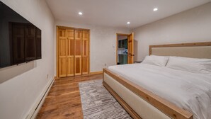 Une chambre avec un grand lit, une armoire en bois et un téléviseur fixé au mur.