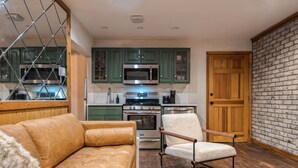 Une cuisine moderne avec des meubles de couleur verte, un four à micro-ondes, une cuisinière et une porte en bois.