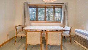 Un comedor con una mesa y cuatro sillas, una ventana con cortinas y una lámpara en el techo.