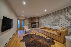 Una sala de estar moderna con chimenea de ladrillo, sofá de cuero y una alfombra de piel grande.