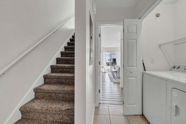 A staircase leading to a laundry area with a white door and a washing machine.