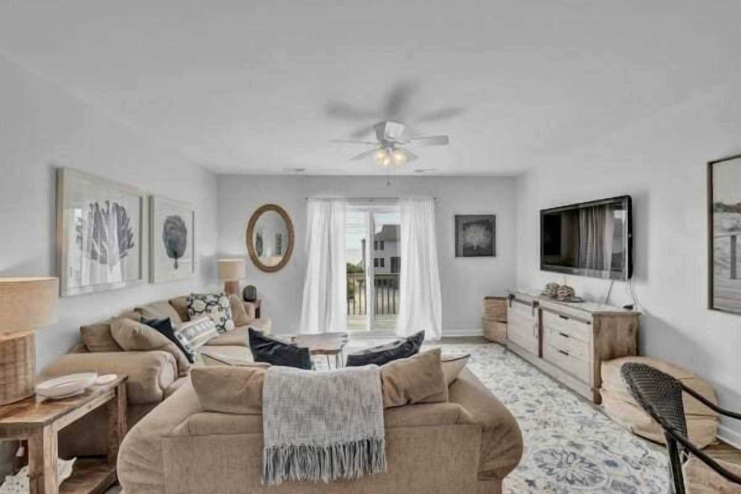 A living room with a sofa, TV, and ceiling fan.