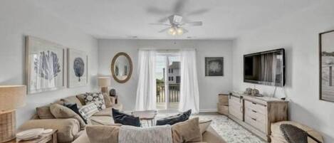 A living room with a sofa, TV, and ceiling fan.