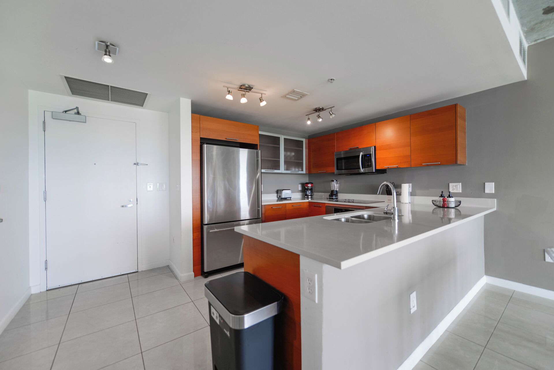 A modern kitchen with a stainless steel refrigerator, a microwave, and a large island with a sink.