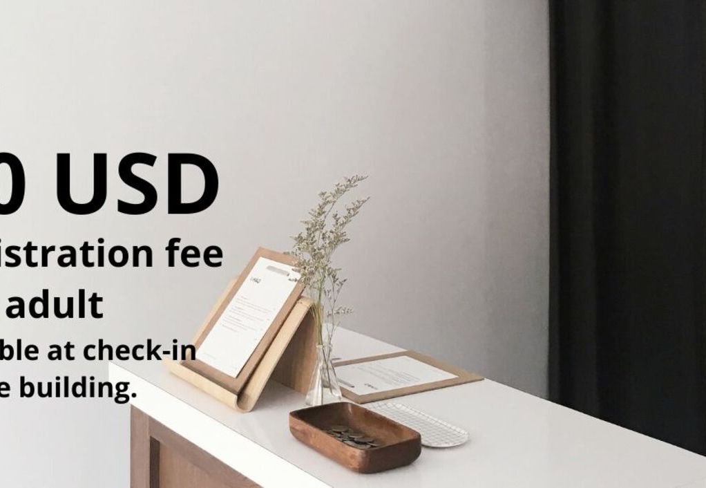 A reception desk with a registration fee notice of 50 USD per adult, payable at check-in in the building.