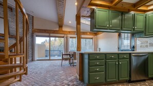 Een keuken met groene kastjes, een tegelvloer en een houten plafond.