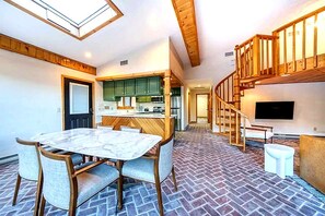 Un vaste espace de vie comprenant un coin repas, une cuisine et un escalier menant à l’étage supérieur.