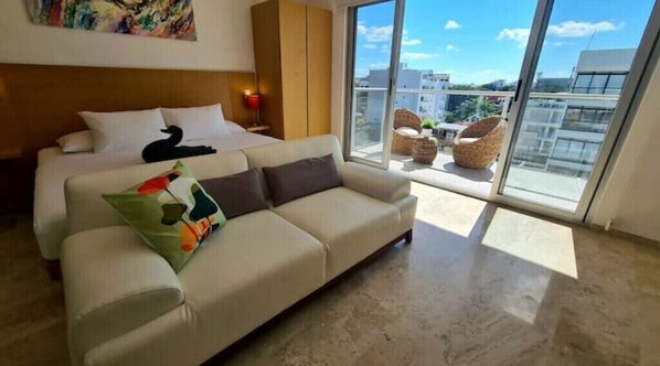 Relax in this stylish room with a large bed, sofa, and balcony offering a view of the surrounding buildings.