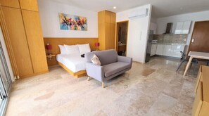 Relax in a spacious room with a large bed, sofa, and kitchenette.