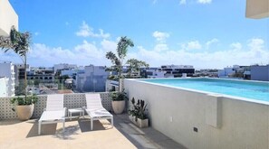 Relax by the pool on a spacious rooftop terrace with a refreshing swimming pool, lounge chairs, and lush greenery.