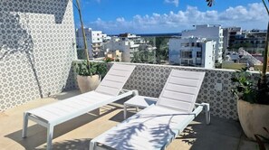 Relax on the rooftop with a view of the city from this tranquil outdoor space, featuring a pair of lounge chairs and a small table.