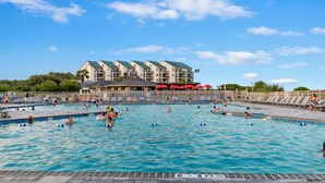 A swimming pool area with multiple lanes, a building with a green roof, and a flag on top. - 2 BR Updated Admirals Row at HH Beach and Tennis Bikes & Beach Gear included (Hilton Head Island)