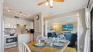 A modern kitchen with white cabinets, a wooden dining table set for four, and a ceiling fan. - 2 BR Updated Admirals Row at HH Beach and Tennis Bikes & Beach Gear included (Hilton Head Island)
