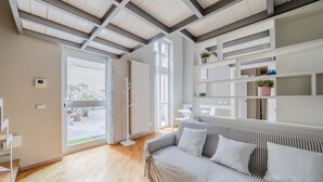A modern living room with a striped sofa, a white shelving unit, and a wooden floor.