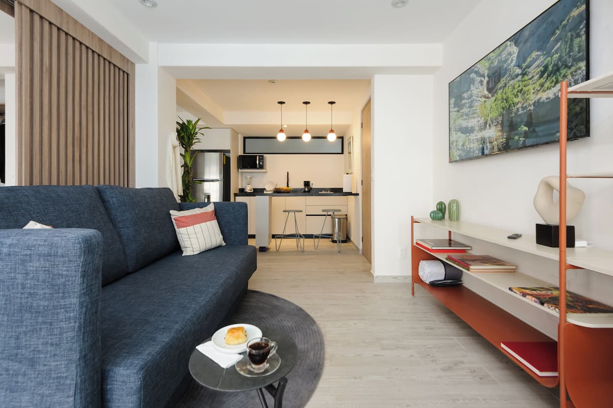 Een moderne woonkamer met een bank, een salontafel en een eethoek op de achtergrond.