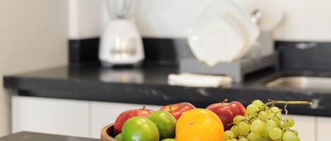 A kitchen counter with a wooden bowl of fruit and a microwave above it.