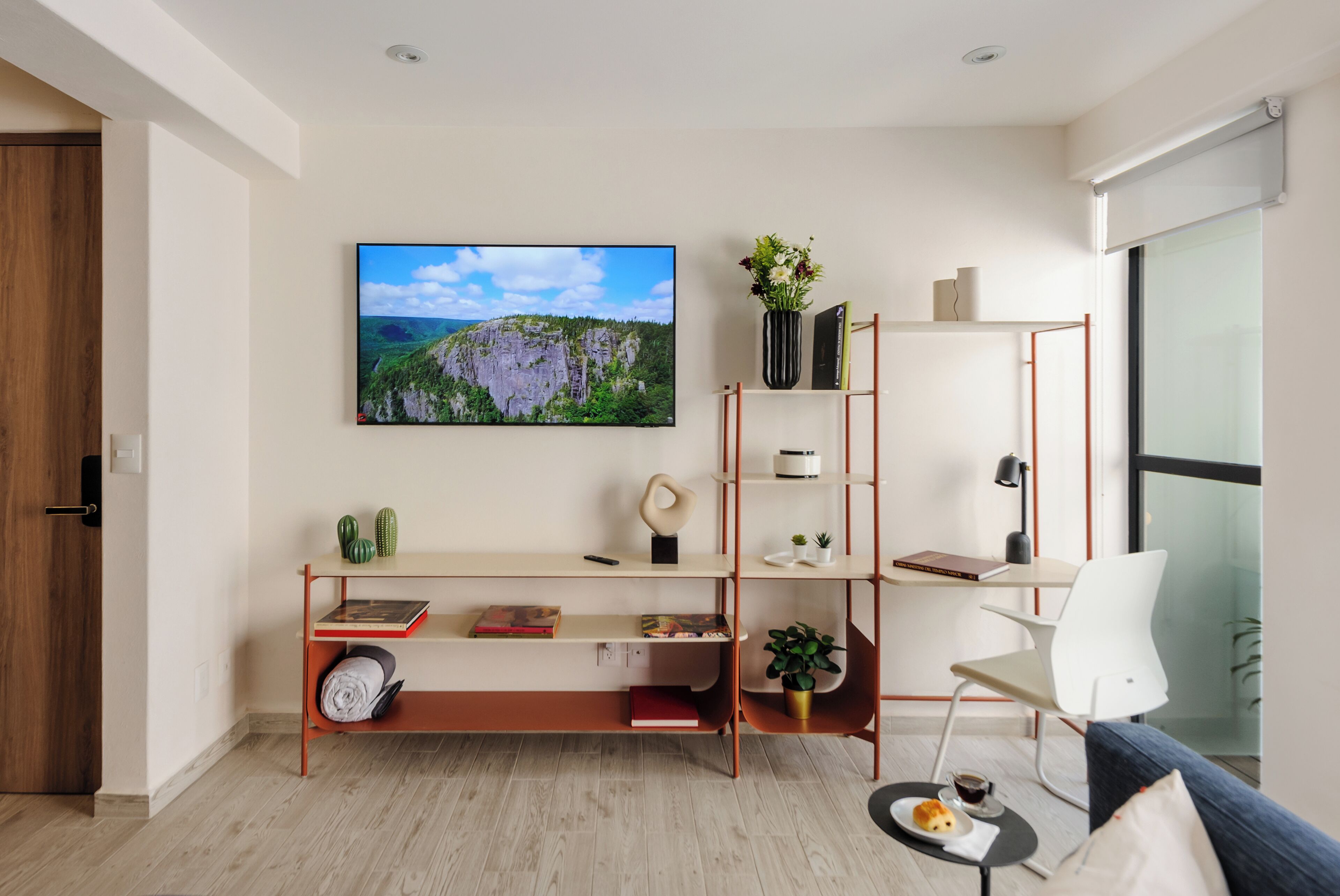 Een moderne woonkamer met houten vloer, een boekenkast, een flatscreen-televisie en een bank.