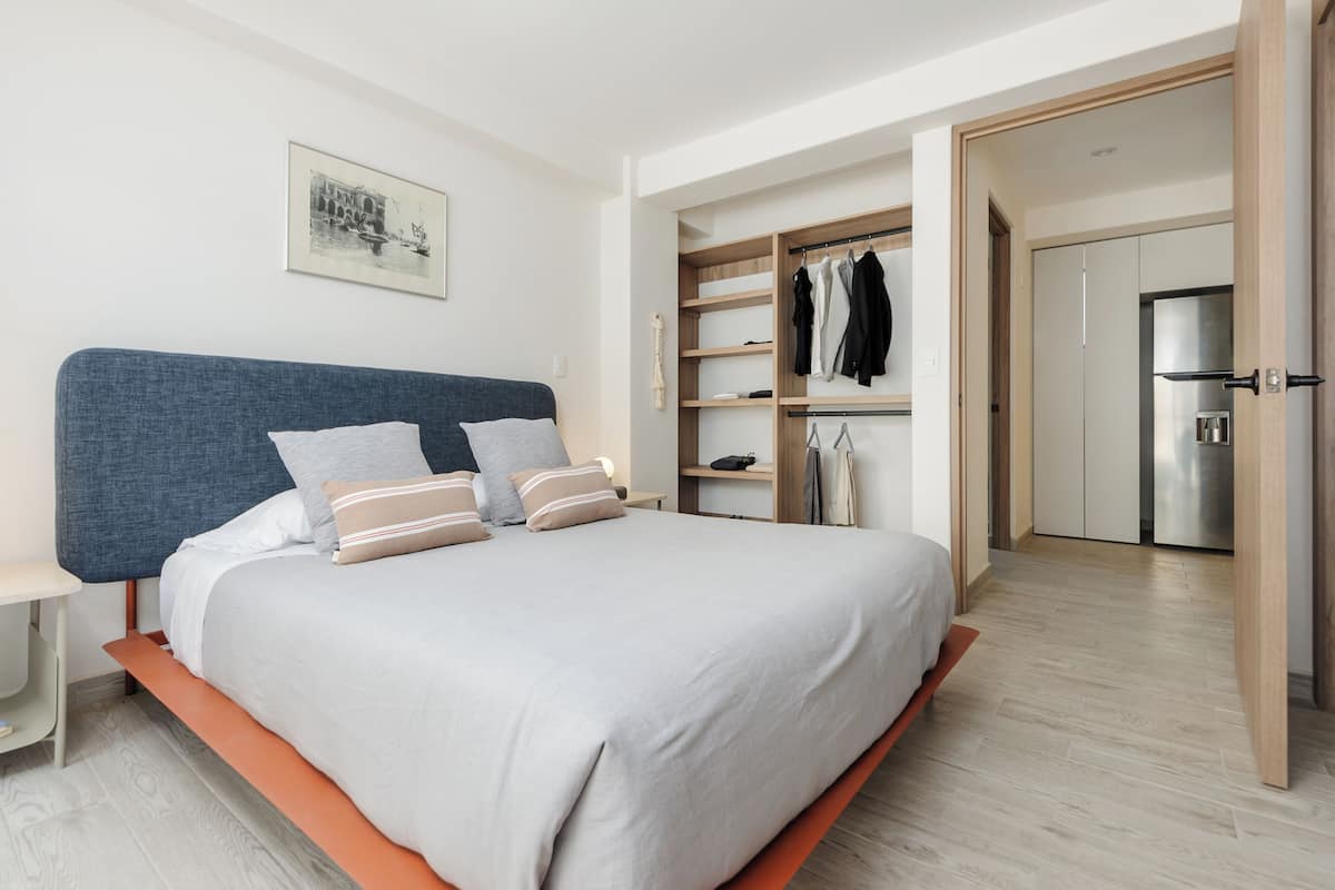 Een moderne slaapkamer met een groot bed, een kledingkast en een inbouwkast met planken.