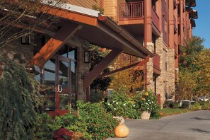 Stunning building with a glass door entrance, brick and wood construction, and a balcony with metal railing.