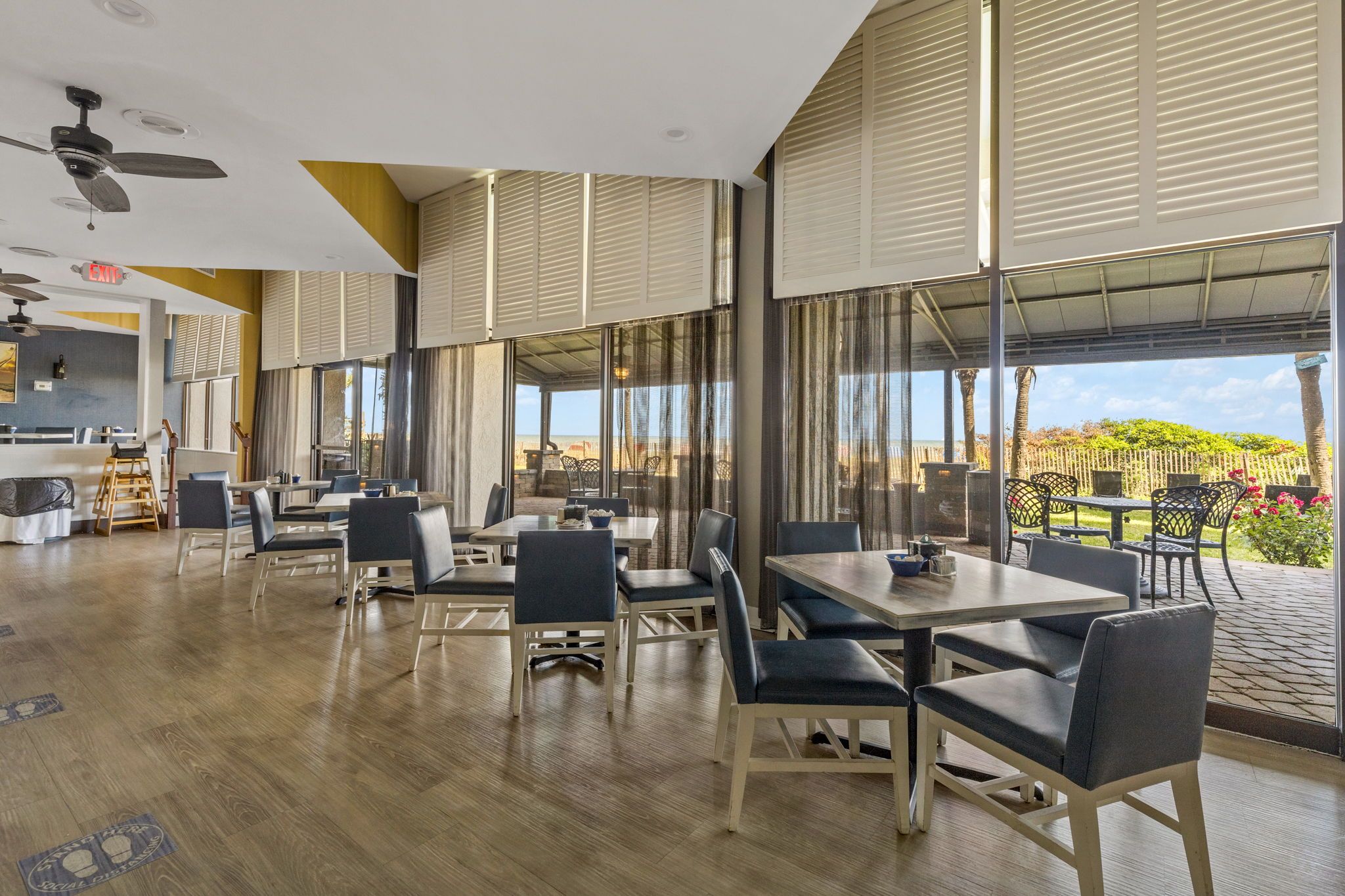 Un comedor amplio con ventanas grandes, suelo de madera y mobiliario moderno.