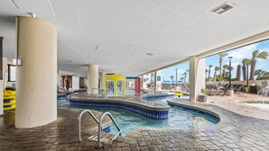 Zona de piscina amb un bany d'hidromassatge, gandules i vistes a palmeres.