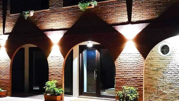 A brick building with arched doorways and potted plants. - Relais Galatea (Montecorvino Pugliano)
